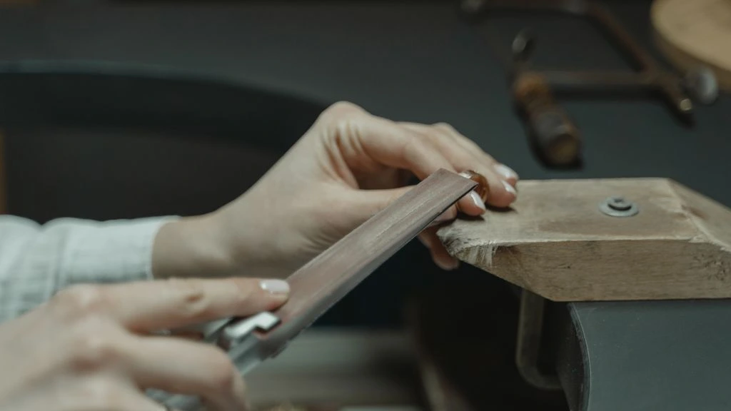 A jeweller's hands at a Lyon atelier bench, working a brass ring in late afternoon light.