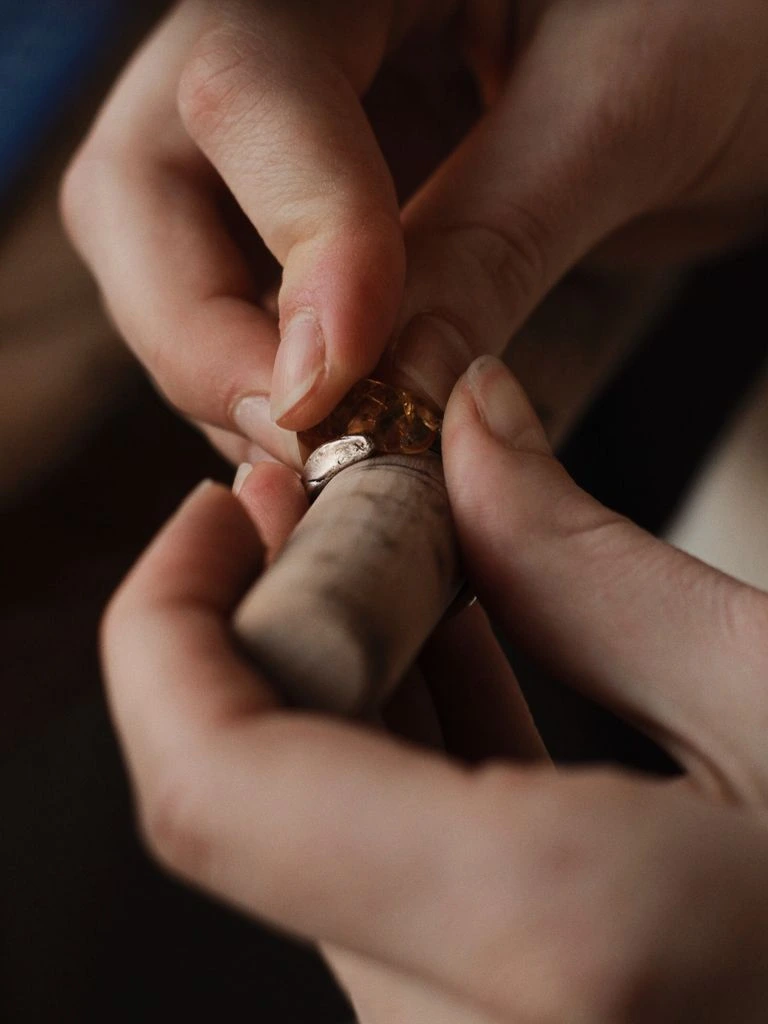 In-house goldsmith setting a smoky quartz stone into brass.