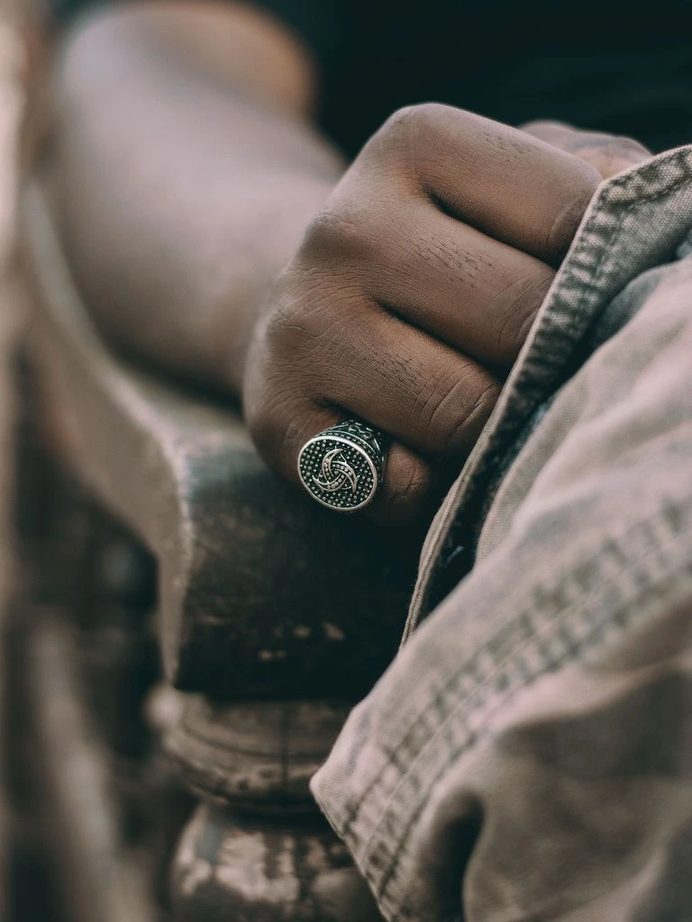 A silver signet ring with an engraved monogram, beside an engraver's tool.